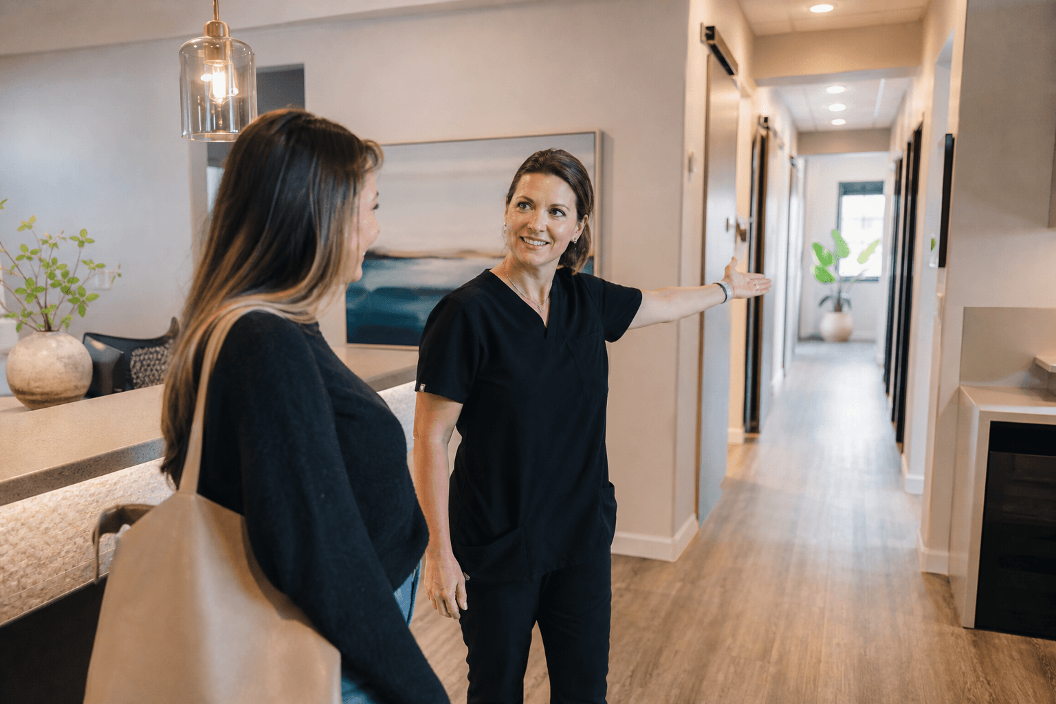 Practice manager giving a visitor a tour of a bright clinic reception