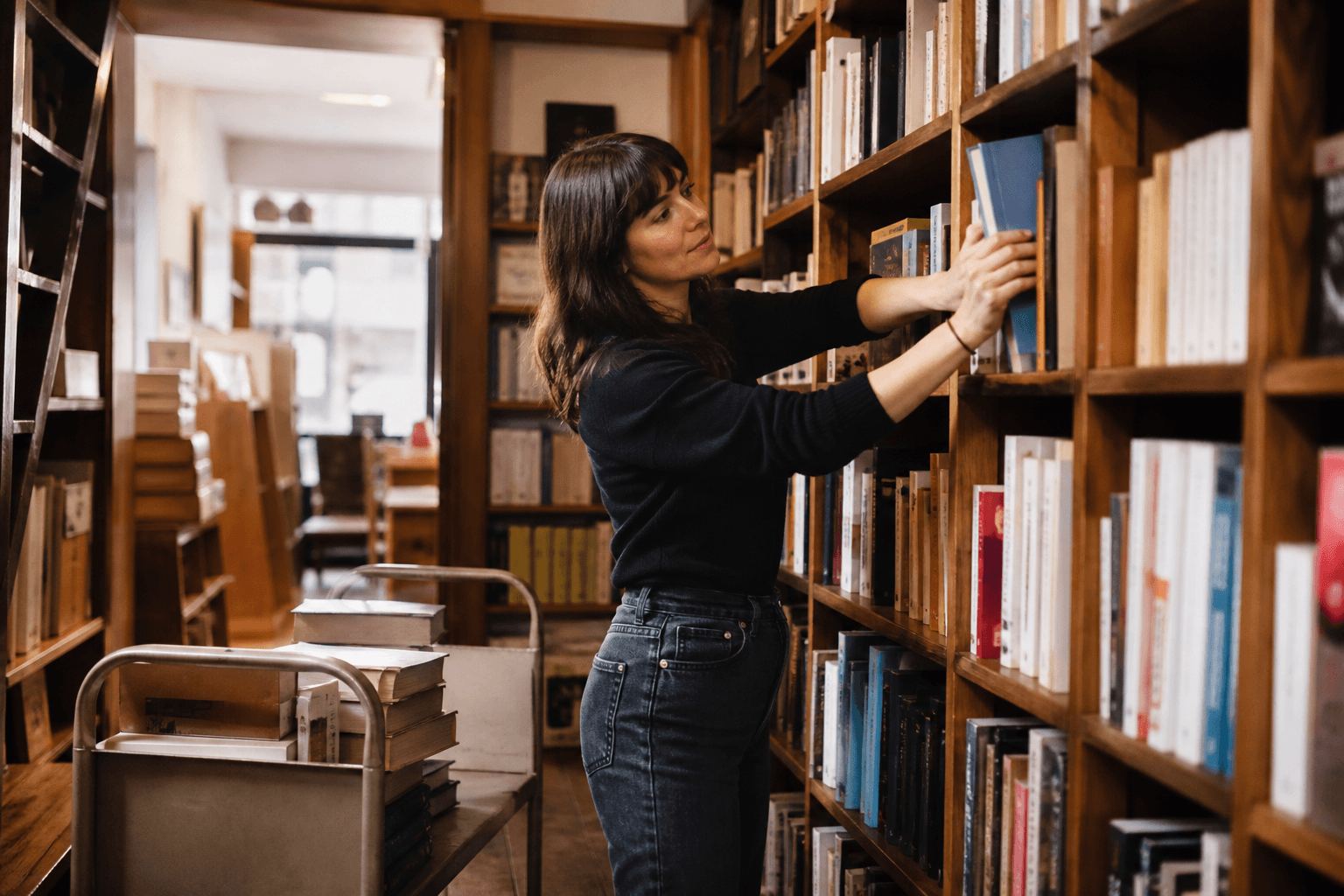Bookshop owner shelving new arrivals from a cart